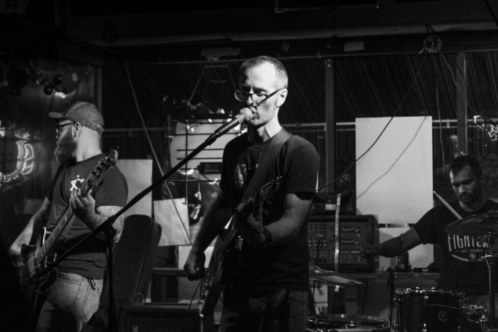 CKS_2-1024x683-1 Band performing live on stage, black-and-white.