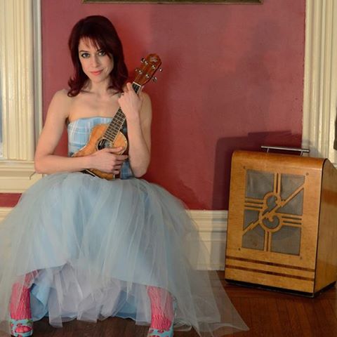 10151233_746176095407535_643440766_n-1 Woman in dress holding a ukulele indoors.