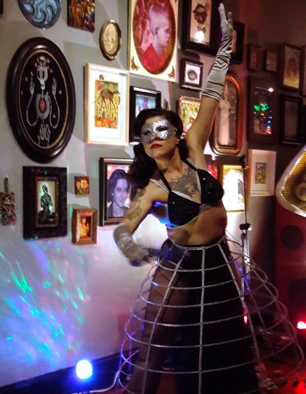 MISSJ-1 Performer in costume posing near art wall.