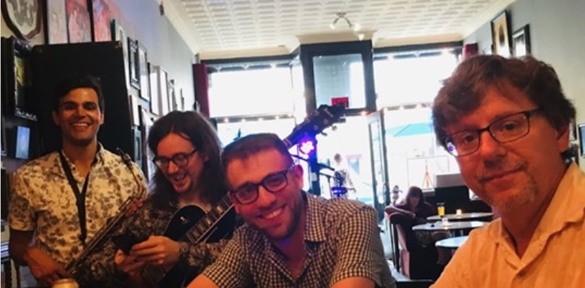 JOHN_BACON_JAZZ-1 Group of people smiling in a cafe.