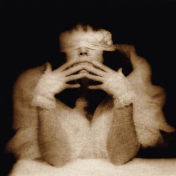 Blindfolded person with hands covering face.