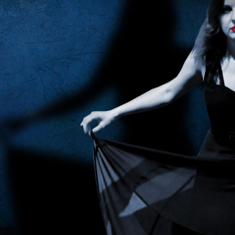 Print A woman in black dress holding onto a sheer cloth.