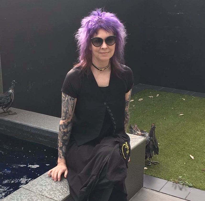 KERRI_HOBBA_PIC-copy-1 Person with purple hair sitting by water.