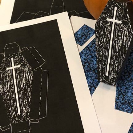 Coffin-shaped paper crafts with cross designs.