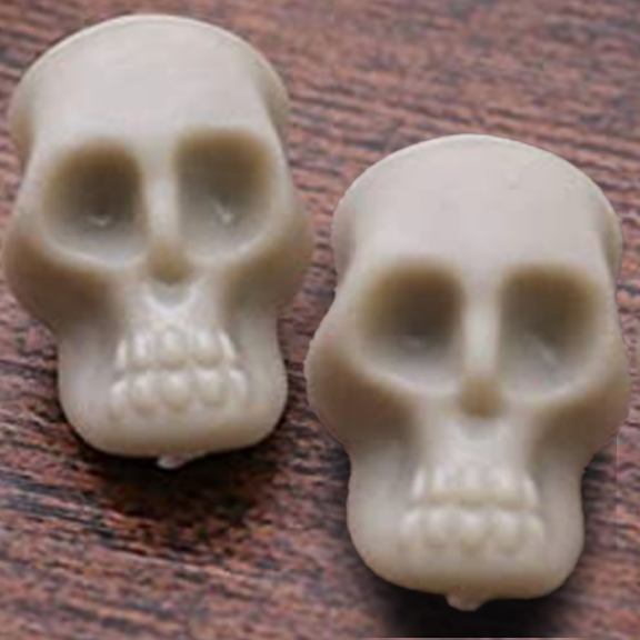 DAY21_SKULLS-1 Two white skull-shaped candles on table.