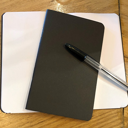 DAY7_JOURNAL-1 Notebook and pen on a wooden table.