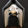 A doll in a black dress with bees on it.
