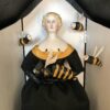 A doll dressed in black and yellow with bees.