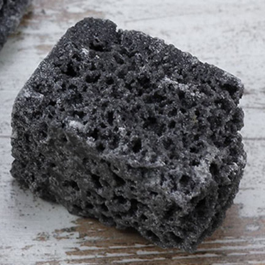 LUMP_OF_COAL-1 Black pumice stones on wooden surface.