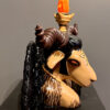 A statue of a horned animal with a candle in it's mouth.