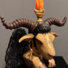 A statue of an animal with horns and a candle.